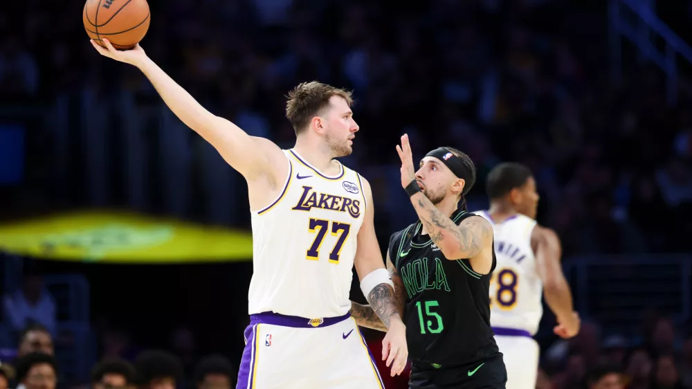 Los Angeles Lakers guard Luka Doncic (77) holds the ball against New Orleans Pelicans guard Jose Alvarado (15) as Los Angeles Lakers forward Rui Hachimura, right, runs during the first half of an NBA basketball game, Sunday, Nov. 30, 2025, in Los Angeles. (AP Photo/Jessie Alcheh)