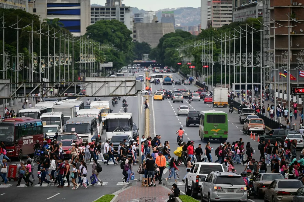 Pedestrians cross an avenue, after U.S. President Donald Trump said on Saturday that the airspace above and around Venezuela would be completely closed, amid rising tensions between the Trump administration and the government of Venezuelan President Nicolas Maduro, in Caracas, Venezuela, November 29, 2025. REUTERS/Gaby Oraa