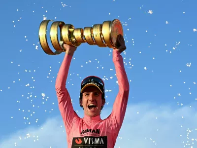Cycling - Giro d'Italia - Stage 21 - Rome to Rome - Italy - June 1, 2025 Team Visma | Lease a Bike's Simon Yates celebrates with a trophy on the podium after winning the Giro d'Italia REUTERS/Jennifer Lorenzini  TPX IMAGES OF THE DAY
