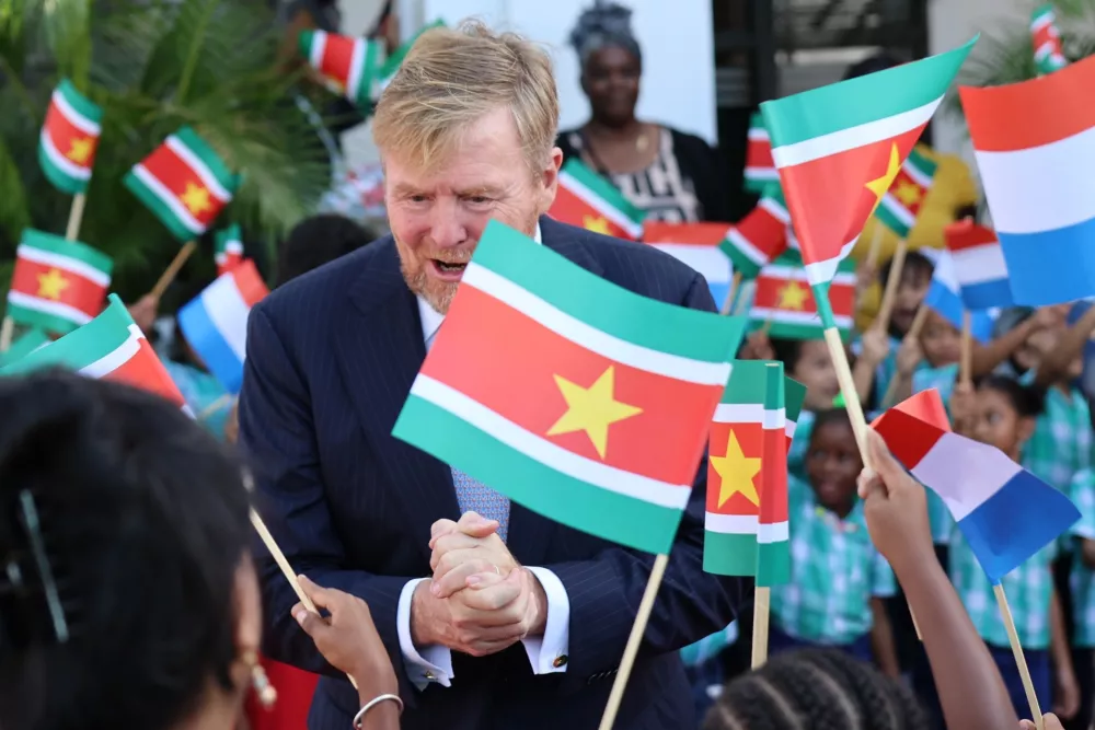 The Netherlands' King Willem-Alexander greets people among Surinamese and Dutch flags during an official welcome ceremony marking Suriname's 50th independence anniversary, at the presidential palace in Paramaribo, Suriname, Monday, Dec. 1, 2025. (AP Photo/Bentik Paulus)