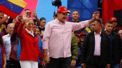 Venezuela's President Nicolas Maduro waves while holding the hand of his wife Cilia Flores during a ceremony to swear in new community-based organisations, as U.S. President Donald Trump's administration ramps up pressure on Maduro's government, in Caracas, Venezuela, December 1, 2025. REUTERS/Leonardo Fernandez Viloria