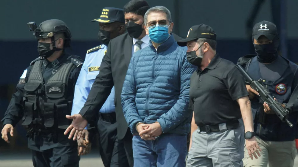 FILE PHOTO: Honduras former President Juan Orlando Hernandez is escorted by authorities as he walks towards a plane of the U.S. Drug Enforcement Administration (DEA) for his extradition to the United States, to face a trial on drug trafficking and arms possession charges, at the Hernan Acosta Mejia Air Force base in Tegucigalpa, Honduras April 21, 2022. REUTERS/Fredy Rodriguez/File Photo