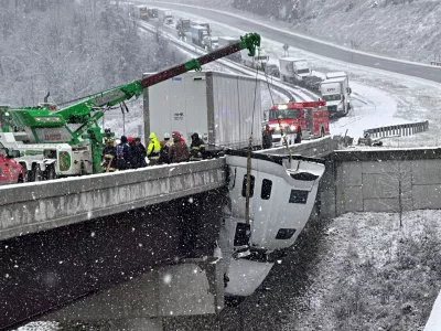 This photo provided by Vickie Flora shows crews working to remove a truck cab dangling from a bridge along U.S. Route 35 after it crashed in icy conditions Tuesday, Dec. 2, 2025, in Southside, W.Va. (Vickie Flora via AP)