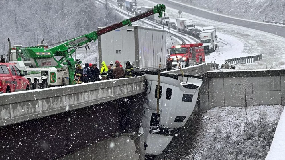 This photo provided by Vickie Flora shows crews working to remove a truck cab dangling from a bridge along U.S. Route 35 after it crashed in icy conditions Tuesday, Dec. 2, 2025, in Southside, W.Va. (Vickie Flora via AP)