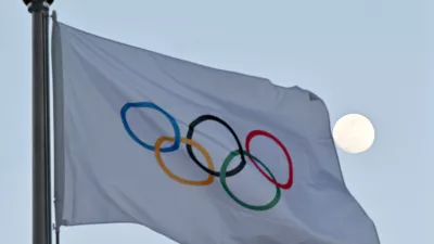 FILED - 14 February 2022, China, Beijing: The moon can be seen behind the flag with the Olympic rings. The International Olympic Committee (IOC) has agreed on a new  billion deal with long-time partners NBC for the United States broadcast rights for the 2034 and 2036 Games. Photo: Peter Kneffel/dpa