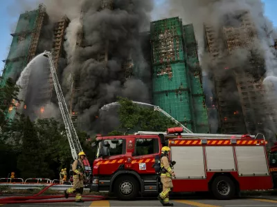 Firefighters walk near the site of a major fire at Wang Fuk Court housing complex, during a deadly fire, in Tai Po, Hong Kong, China, November 26, 2025. REUTERS/Tyrone Siu     SEARCH "HONG KONG FIRE PICTURE" FOR THIS STORY. SEARCH "WIDER IMAGE" FOR ALL STORIES.