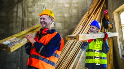 Two construction workers carrying a scaffolding at a building site - people at work concepts / Foto: Jovanmandic