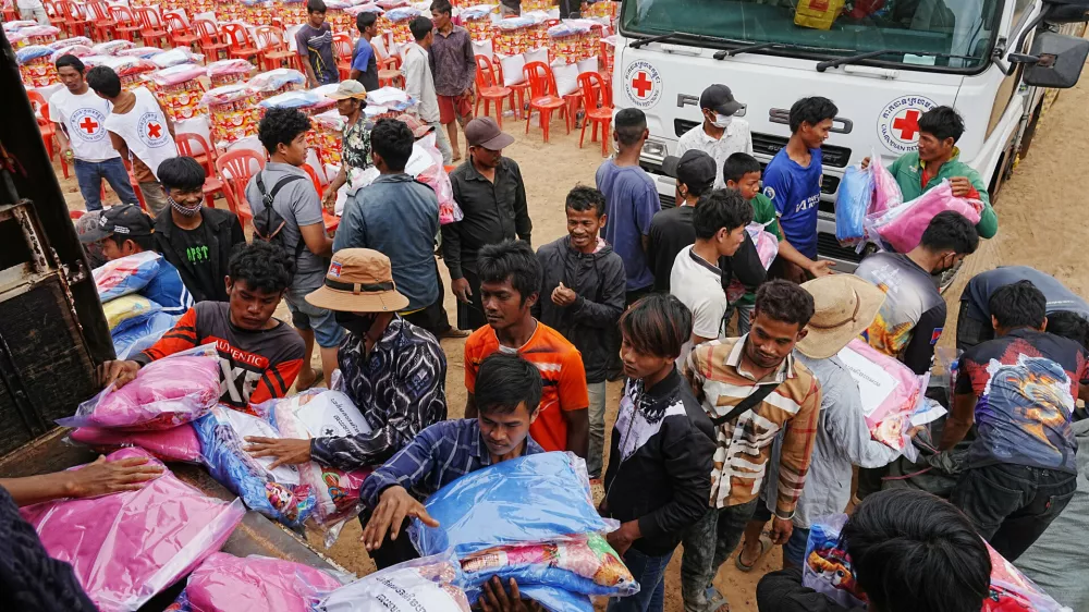 Yong evacuees help other evacuees to carry donation at Batthkoa Buddhist pagoda in Oddar Meanchey province, Cambodia Wednesday, Dec. 10, 2025, after fleeing from home following a fighting between Thailand and Cambodia over territorial claims (AP Photo/Heng Sinith)