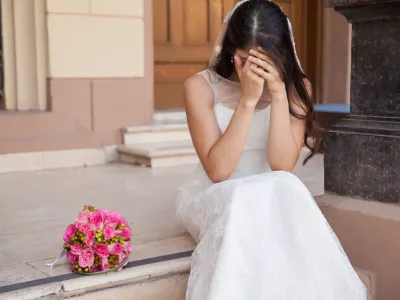 Hopeless bride crying outside a church after being stood up on her wedding day