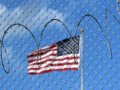 FILED - 15 January 2023, Cuba, Guant?namo: A U.S. flag flies behind barbed wire at the Guant?namo Bay naval base in Cuba. The US government flew 177 deportees from Guantanamo Bay to Honduras on 20 February. US border protection agency ICE said the deportees were then picked up and returned home by the Venezuelan government. Photo: Magdalena Miriam Tr?ndle/dpa