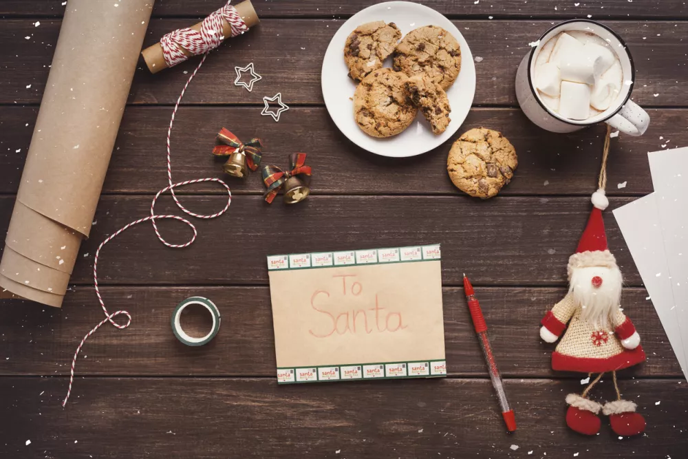 Magic Christmas moments. Dear Santa letter on workplace with cookies, hot chocolate and decorations