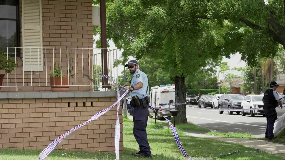 A police officer removes police tape from outside the house of the suspects of a shooting incident on a Jewish holiday celebration at Bondi Beach, in Bonnyrigg, Sydney, Australia, December 15, 2025. REUTERS/Alasdair Pal