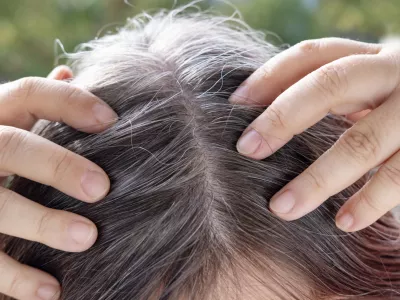 Aging with grace and confidence, brown-haired woman with long brown hair with gray hair, female forehead close-up, hands hold strands of hair, Hair care and grooming for mature women / Foto: Victor Golmer