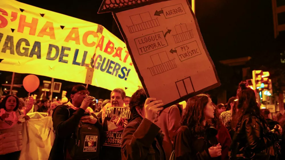 FILE PHOTO: A demonstrator holds a house-shaped sign that reads "from touristic flat to temporary rent to Airbnb" during a protest to demand lower housing rental prices and better living conditions, in Barcelona, Spain, November 23, 2024. REUTERS/Bruna Casas/File Photo