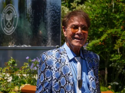 FILE - Singer Cliff Richard poses for a photo as he arrives for day eleven at the Wimbledon Tennis Championships in London, July 10, 2025. (AP Photo/Joanna Chan, File)