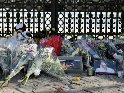 Photos of the two victims, Mukhammad Aziz Umurzokov and Ella Cook, rest among the flowers in front of the Van Wickle Gates as the manhunt continues for the gunman, following a shooting at Brown University in Providence, Rhode Island, U.S. December 16, 2025. REUTERS/Taylor Coester