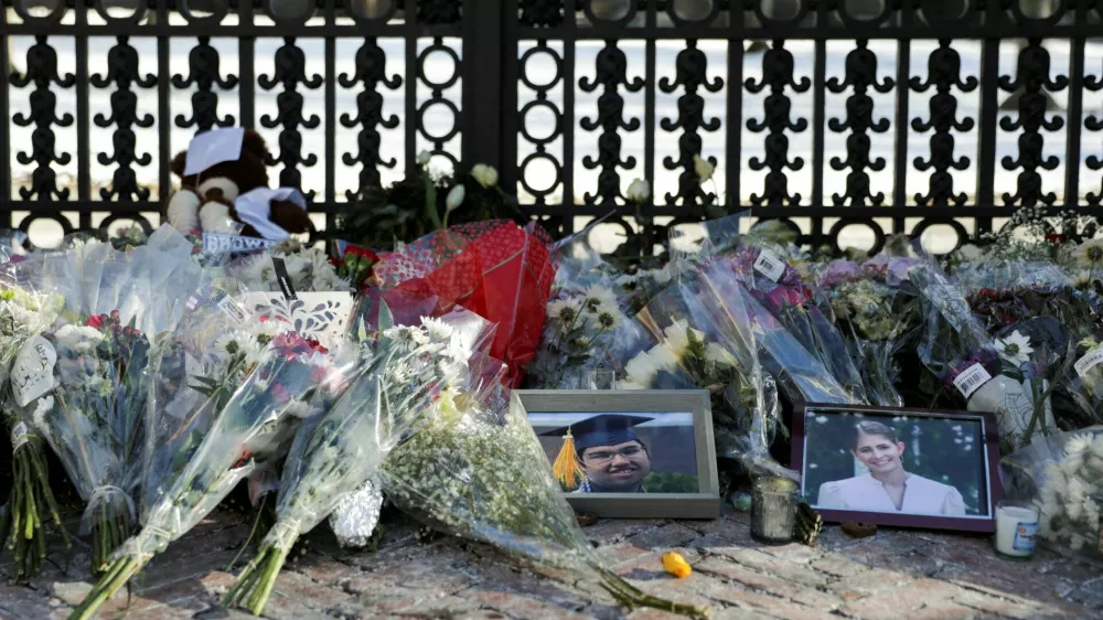 Photos of the two victims, Mukhammad Aziz Umurzokov and Ella Cook, rest among the flowers in front of the Van Wickle Gates as the manhunt continues for the gunman, following a shooting at Brown University in Providence, Rhode Island, U.S. December 16, 2025. REUTERS/Taylor Coester