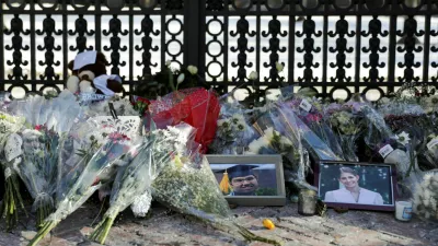 Photos of the two victims, Mukhammad Aziz Umurzokov and Ella Cook, rest among the flowers in front of the Van Wickle Gates as the manhunt continues for the gunman, following a shooting at Brown University in Providence, Rhode Island, U.S. December 16, 2025. REUTERS/Taylor Coester