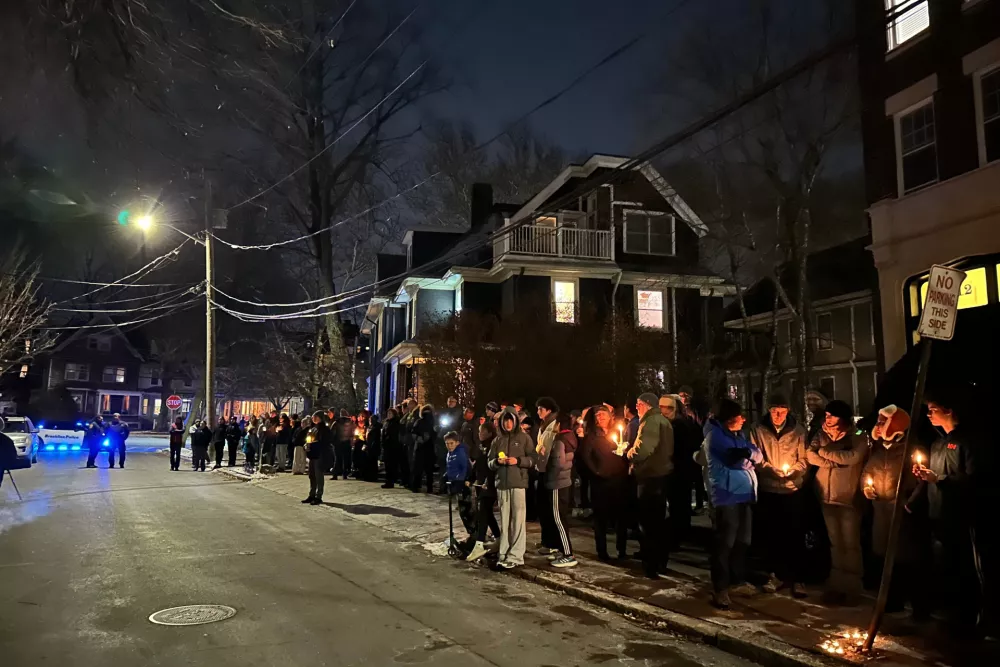 A crowd of people holding candles gather outside the home of Massachusetts Institute of Technology professor Nuno F.G. Loureiro in Brookline, Mass., Tuesday, Dec. 16, 2025. (AP Photo/Leah Willingham)