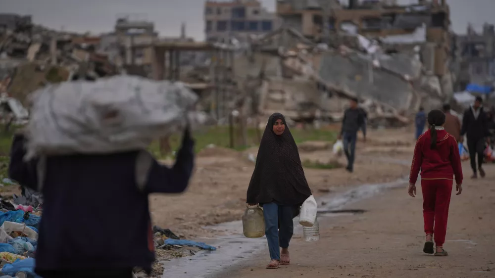 A Palestinian woman carries a container of water in Nuseirat, central Gaza Strip, Friday, Jan. 2, 2026. (AP Photo/Abdel Kareem Hana) / Foto: Abdel Kareem Hana