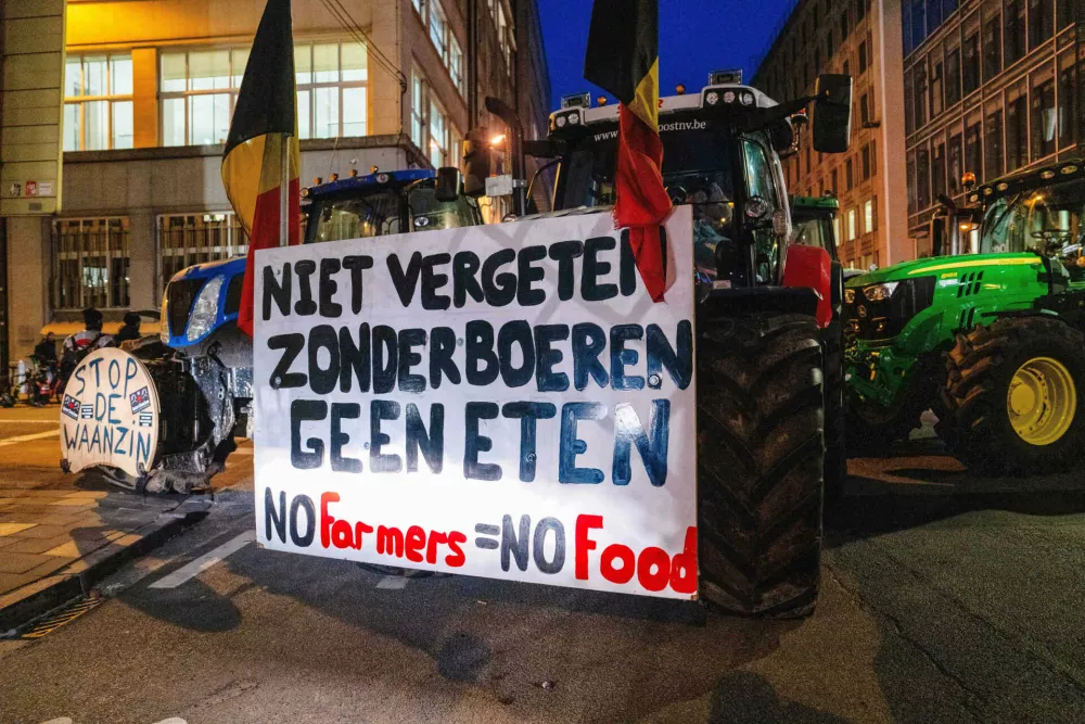 A farmer drives a tractor with a sign that reads in Dutch 'Don't forget, without farmers there's no food' during a demonstration outside a gathering of European leaders at the EU Summit in Brussels, Thursday, Dec. 18, 2025. (AP Photo/Marius Burgelman)
