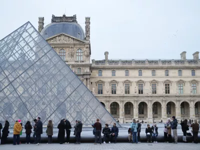 People wait for the Louvre museum to open as employees at the Louvre Museum vote to extend a strike that has disrupted operations at the world's most visited museum, Thursday, Dec. 18, 2025 in Paris. (AP Photo/Thibault Camus)