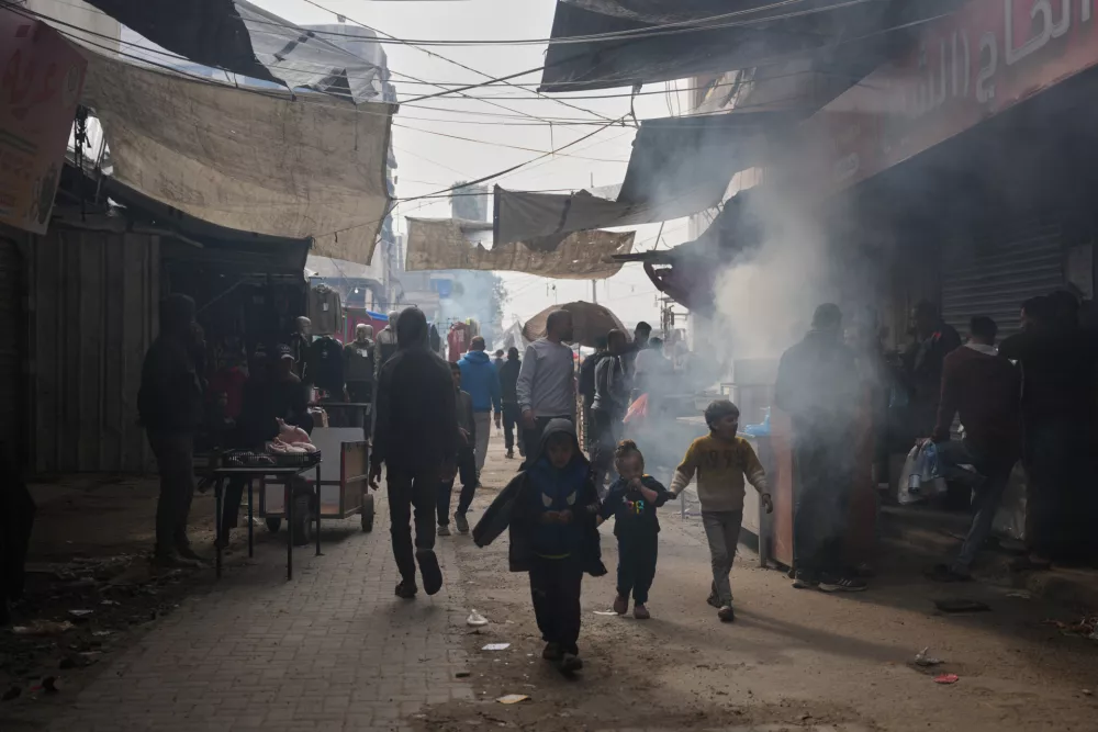Palestinians walk along a street market where fruits and vegetables are displayed for sale in Gaza City, Friday, Dec. 19, 2025. (AP Photo/Abdel Kareem Hana)