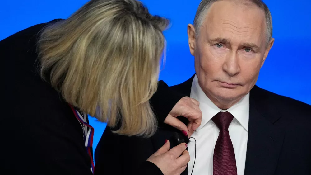 A TV assistant attaches a microphone to Russian President Vladimir Putin's suit prior to his annual news conference and call-in show at Gostinny Dvor, in Moscow, on Friday, Dec. 19, 2025. (AP Photo/Pavel Bednyakov)
