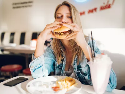 Young woman eating burger in restaurant / Foto: Diem.ph