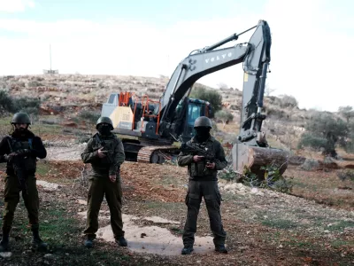 NABLUS, WEST BANK - DECEMBER 08: Israeli soldiers stand by as Israeli construction vehicles destroy agricultural lands and uproot centuries-old olive trees in the village of Karyut, south of the city of Nablus, West Bank on December 08, 2025. Palestinian farmers stated that the trees are the 'memory of the village,' while noting that hundreds of acres of land in the area are being targeted for a new settlement project. Issam Rimawi / AnadoluNo Use USA No use UK No use Canada No use France No use Japan No use Italy No use Australia No use Spain No use Belgium No use Korea No use South Africa No use Hong Kong No use New Zealand No use Turkey
