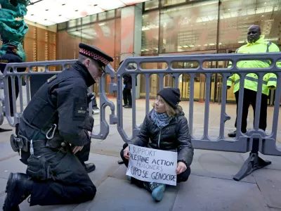 In this photo, released by 'Prisoners for Palestine' on Tuesday, Dec. 23, 2025, climate activist Greta Thunberg, center, sits in front of offices of Aspen Insurance in London, England, during a protest to support the Palestine Action protesters on hunger strike in prison. (Prisoners for Palestine via AP)