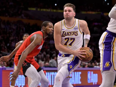 Los Angeles Lakers guard Luka Doncic (77) drives to the basket past Houston Rockets forward Kevin Durant during the second half of an NBA basketball game, Thursday, Dec. 25, 2025, in Los Angeles. (AP Photo/Jayne Kamin-Oncea)