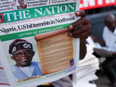 People read newspapers reporting on U.S. airstrikes against Islamic State militants in Nigeria, according to U.S. President Donald Trump and the U.S. military, in Lagos, Nigeria, December 26, 2025. REUTERS/Sodiq Adelakun