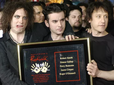 FILE - Robert Smith, left, Simon Gallup, center, and Perry Bamonte of British rock group The Cure hold a plaque after being inducted into Hollywood's Rockwalk in Los Angeles, Friday, April 30, 2004. (AP Photo/Chris Pizzello, File)