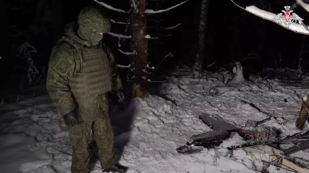 A Russian service member stands next to the remains of a drone, which, according to the Russian Defence Ministry, was downed during the repelling of an alleged Ukrainian attack on the Russian presidential residence in the Novgorod Region, in an unknown location in Russia, in this still image from a video released December 31, 2025. Russian Defence Ministry/Handout via REUTERS ATTENTION EDITORS - THIS IMAGE WAS PROVIDED BY A THIRD PARTY. NO RESALES. NO ARCHIVES. MANDATORY CREDIT. WATERMARK FROM SOURCE.