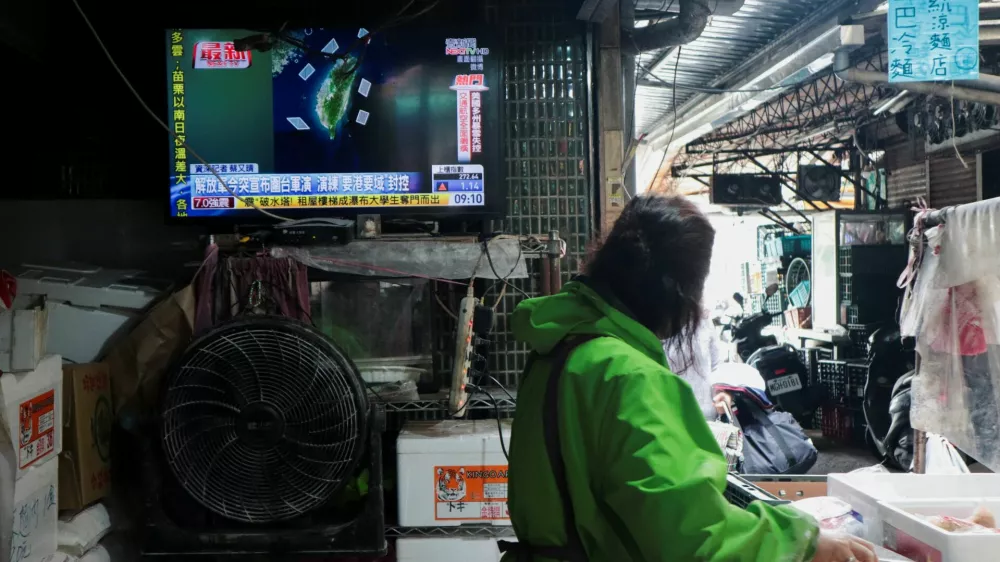 A woman works in a noodle store near a television screen showing a news report on China's "Justice Mission 2025" military drills around Taiwan, in Taipei, Taiwan, December 29, 2025. REUTERS/Tsai Hsin-Han