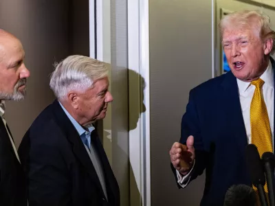 President Donald Trump, accompanied by Commerce Secretary Howard Lutnick, left, and Sen. Lindsey Graham, R-S.C., speaks with reporters while in flight on Air Force One, Sunday, Jan. 4, 2026, as returning to Joint Base Andrews, Md. (AP Photo/Alex Brandon)