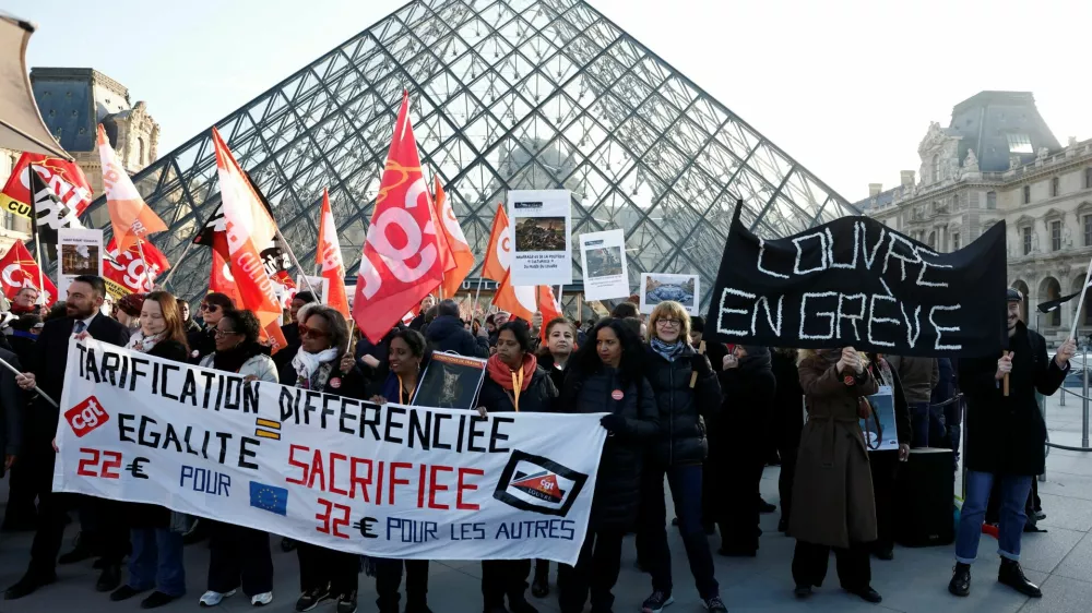 Louvre museum employees on strike hold a banner which reads "Louvre on strike" and CGT, CFDT Culture and Sud Solidaires labour unions flags near the glass Pyramid of the Louvre museum to protest their working conditions, the state of the museum's buildings and staffing issues, two months after a spectacular heist which saw thieves make off with jewels in broad daylight, in Paris, France, December 15, 2025. REUTERS/Benoit Tessier