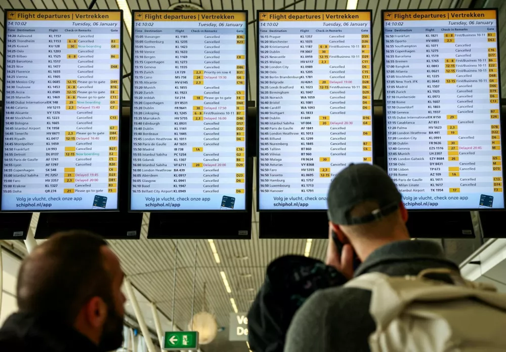 People look at departures screens showing delayed and cancelled flights at Amsterdam Airport Schiphol, as snowfall causes disruptions to air, rail and road traffic in the Netherlands, in Schiphol, Netherlands January 6, 2026. REUTERS/Piroschka van de Wouw