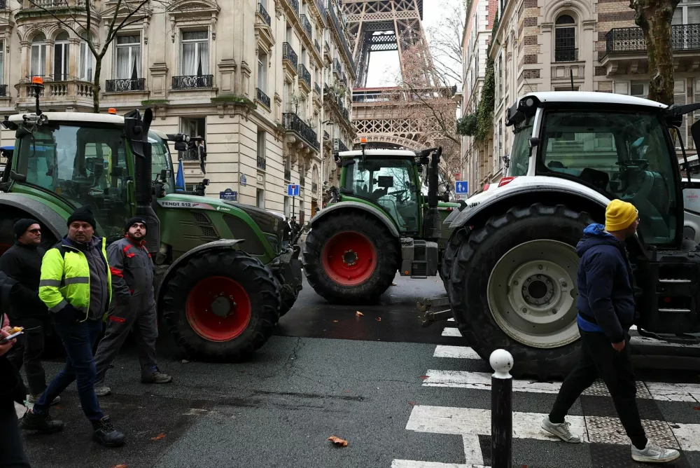 People walk next to tractors blocking a road near the Eiffel Tower, as French farmers protest against the government's handling of the EU-Mercosur free trade agreement and the handling of the lumpy skin disease outbreak, in Paris, France, January 8, 2026. REUTERS/Gonzalo Fuentes