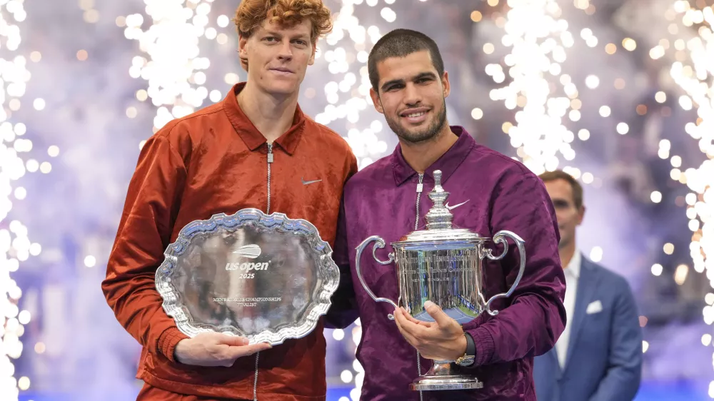 Carlos Alcaraz, of Spain, poses for photos with Jannik Sinner, of Italy, after winning the men's singles final of the U.S. Open tennis championships, Sunday, Sept. 7, 2025, in New York. (AP Photo/Kirsty Wigglesworth)