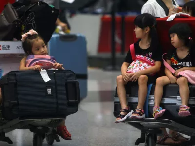 Children sit on the luggage carts as they stranded at the Beijing Capital International Airport after flights are canceled due to the heavy rains in Beijing, China Saturday, July 21, 2012. Heavy downpour flooded roads and caused hundreds of flights to be canceled in the capital. (AP Photo) CHINA OUT