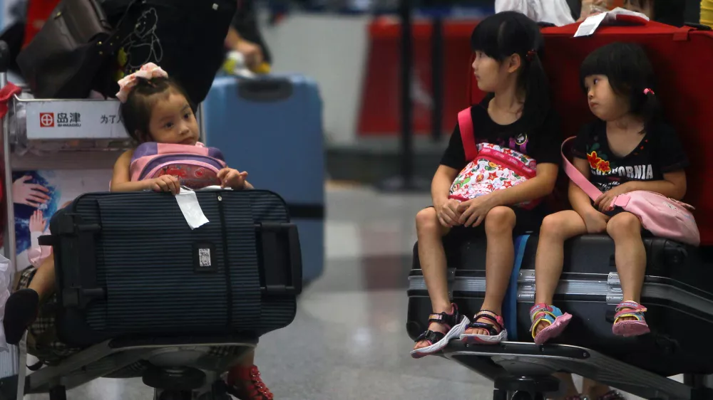 Children sit on the luggage carts as they stranded at the Beijing Capital International Airport after flights are canceled due to the heavy rains in Beijing, China Saturday, July 21, 2012. Heavy downpour flooded roads and caused hundreds of flights to be canceled in the capital. (AP Photo) CHINA OUT