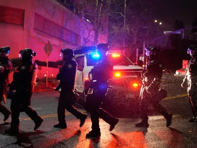 Portland police officers walk outside the U.S. Immigration and Customs Enforcement facility on Thursday, Jan. 8, 2026, in Portland, Ore. (AP Photo/Jenny Kane)