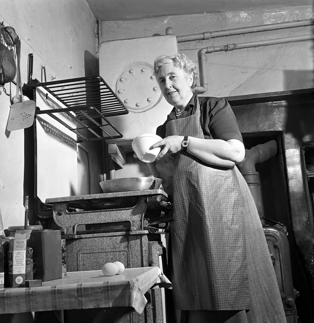 English writer and novelist Agatha Christie (1890-1976) cooking in the kitchen of her home, Winterbrook House near Wallingford, Oxfordshire in 1950. Agatha Christie has written a number of crime novels and stories featuring the fictional detectives Hercule Poirot and Miss Jane Marple. (Photo by Jack Esten/Popperfoto via Getty Images)
