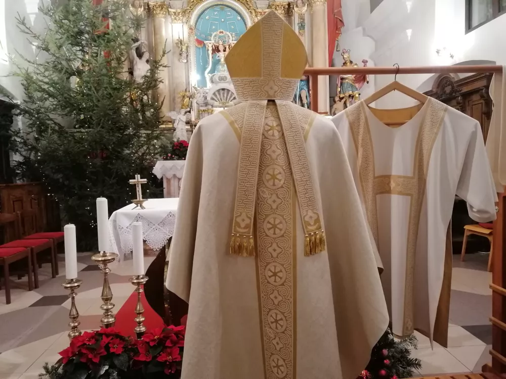 Spodnja Idrija, zupnijska cerkev.Predstavitev masnega plasca in mitre z idrijsko cipko kot darilo papezu.Motiv mitre z idrijsko cipko.