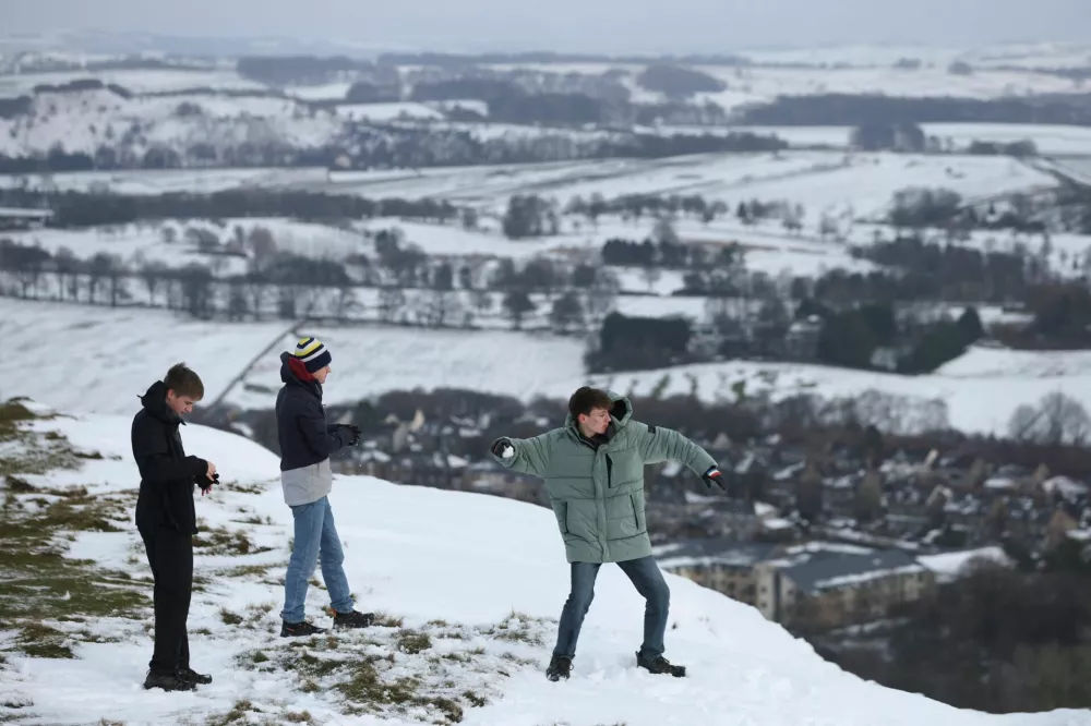Youths stand on the snowy Corbar Hill as one of them throws a snowball, after Storm Goretti's arrival amid a week of plunging temperatures, in Buxton, Britain, January 9, 2026. REUTERS/Temilade Adelaja