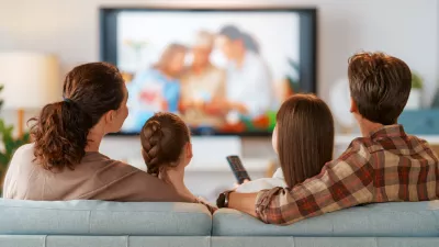 Happy family spending time together. Mother, father and children watching TV, movies with popcorn in the evening at home.