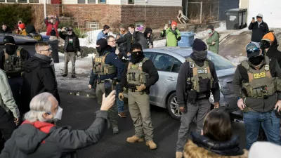 U.S. Immigration and Customs Enforcement (ICE) agents stand by a damaged civilian's car, which was hit by ICE, after an ICE agent fatally shot Renee Nicole Good, in Minneapolis, Minnesota, U.S., January 12, 2026.  REUTERS/Tim Evans