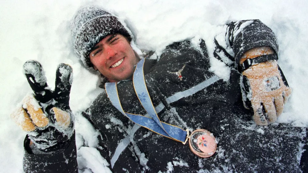 FILE - Swiss snowboarder Ueli Kestenholz rolls around in the snow of Shiga Kogen on Monday, Feb. 9, 1998, adorned with the bronze medal he won the previous day in the Olympic snowboard giant slalom. (Alessandro della Valle/Keystone via AP, file)